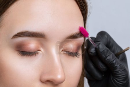 El maquillador hace marcas con un lápiz de cejas blanco y aplica pintura en las cejas. Maquillaje profesional y cuidado de la cara.