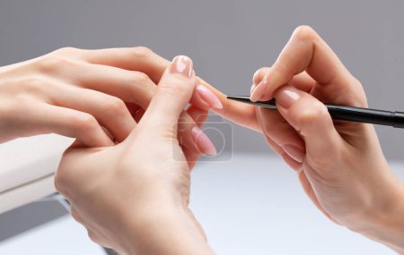 The master of the manicure coats nails with gel polish in the beauty salon. Professional care for hands.