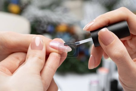 Le maître de la manucure couche les ongles avec du gel poli dans le salon de beauté. Soins professionnels pour les mains. Concept Nouvel An.