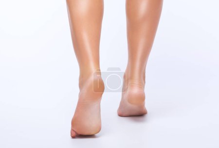Hermosas piernas delgadas de una mujer sobre un fondo blanco. Pies cerca. Cita con el podólogo.