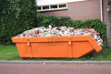 Téléchargez les photos : Old, demolished bricks in an orange garbage dumpster - en image libre de droit
