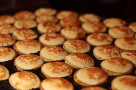 Photo for Poffertjes, Dutch small, fluffy pancakes, made on hot cast iron plate, served with powdered sugar and butter. - Royalty Free Image