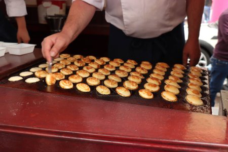 Poffertjes, kleine, flauschige holländische Pfannkuchen, auf heißem gusseisernem Teller, serviert mit Puderzucker und Butter.