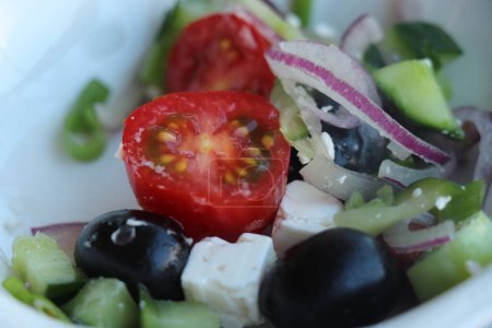 A fresh green mixed greek salad: cheese, onions, olives and lettuce