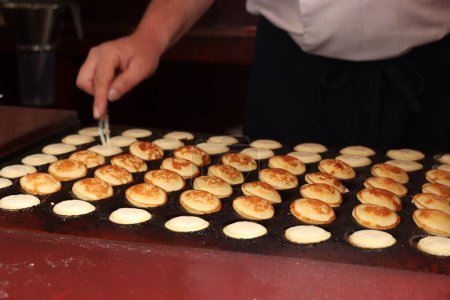Photo for Poffertjes, Dutch small, fluffy pancakes, made on hot cast iron plate, served with powdered sugar and butter. - Royalty Free Image