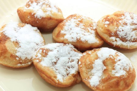 Photo for Poffertjes, Dutch small, fluffy pancakes, served with powdered sugar and butter. - Royalty Free Image