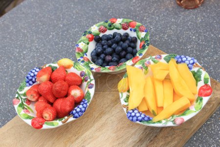 an outdoor summer lunch with fruit in decorated bowls