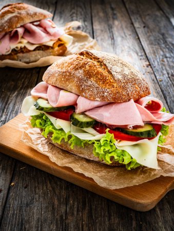 Sandwich mit Mortadella Pistazien, Tapenade und Käse auf Holztisch 