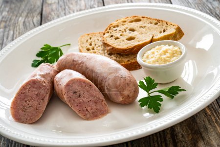 Easter breakfast - boiled white sausages, toasts and horseradish on wooden table 
