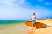 Beautiful woman holding surfboard standing on sunny beach Santa Maria, Sal island , Cape Verde  magic mug #704223322