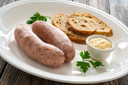 Desayuno de Pascua: salchichas blancas hervidas, pan tostado y rábano picante sobre una mesa de madera 