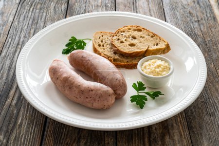 Desayuno de Pascua: salchichas blancas hervidas, pan tostado y rábano picante sobre una mesa de madera 