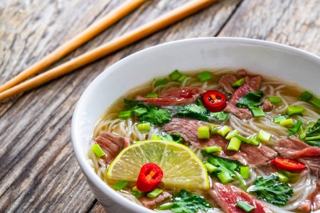 Pho-Suppe - vietnamesische Suppe mit Rindfleisch auf Holztisch 