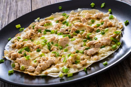 Vietnamese pizza - rice pepper omelet with chicken meat and mushrooms on wooden table 