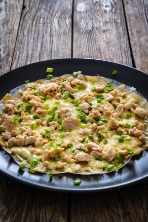 Vietnamese pizza - rice pepper omelet with chicken meat and mushrooms on wooden table 