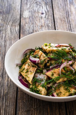 Marinated herring fillets with dill and red onion on wooden table 