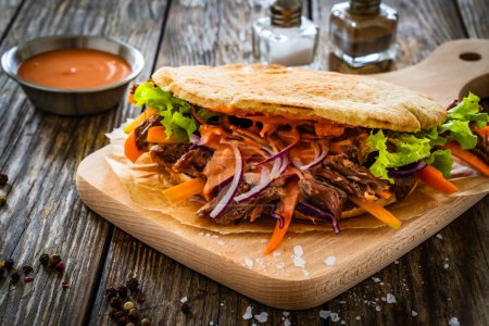 Pita - big sandwich with pulled beef and fresh vegetables on wooden table 
