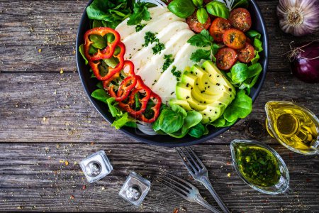 Salade de légumes frais au fromage robiola et avocat sur table en bois 