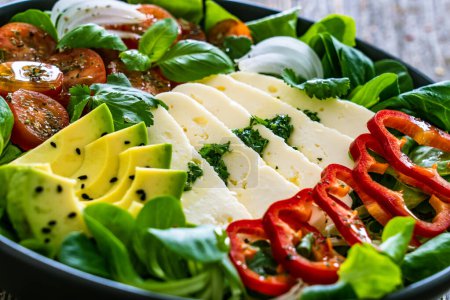 Salade de légumes frais au fromage robiola et avocat sur table en bois 