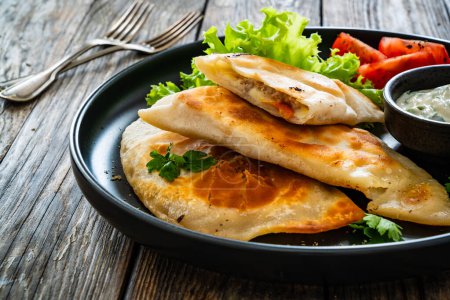 Cheburek - frittierte Teigtaschen gefüllt mit Hackfleisch und Gemüse auf Holztisch 