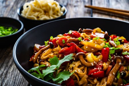  Asian style stir fried vegetables and noodles on wooden table 