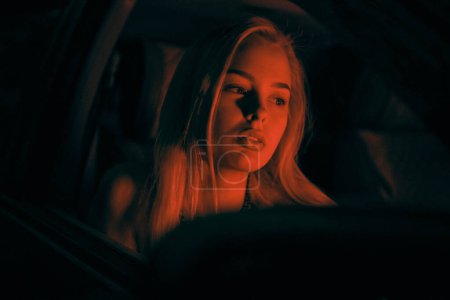 Photo for A beautiful girl of European appearance sits on the passenger seat in the car and looking to the window - Royalty Free Image