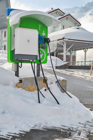 Téléchargez les photos : Borne de recharge pour véhicules électriques près d'une maison en hiver - en image libre de droit