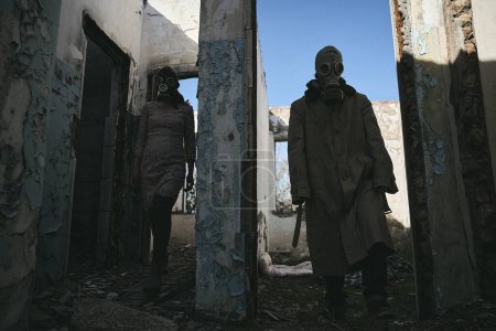 Foto de Un hombre y una mujer en un edificio destruido, con máscaras de gas, salen de diferentes habitaciones, bueno para la portada del libro - Imagen libre de derechos