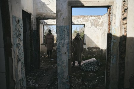 Foto de Un hombre y una mujer en un edificio destruido, con máscaras de gas, de pie en diferentes habitaciones, bueno para la portada del libro - Imagen libre de derechos