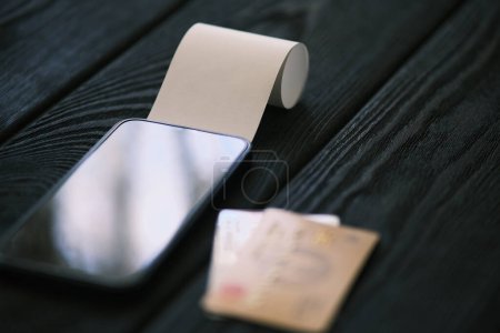 Foto de Un teléfono móvil con un cheque en blanco en la mesa de madera negro, concepto financiero - Imagen libre de derechos