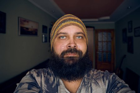 Photo for A man with a beard wearing a striped hat and shirt, looking up into the camera - Royalty Free Image