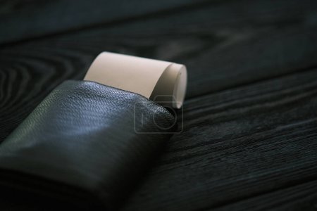 Foto de Un bolso de cuero y una pequeña pila de monedas en la mesa de madera negro, concepto financiero - Imagen libre de derechos