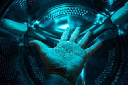 Foto de Una mano dentro de la lavadora en una luz azul, futuro, ciencia ficción, concepto - Imagen libre de derechos