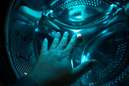 Foto de Una mano dentro de la lavadora en una luz azul, futuro, ciencia ficción, concepto - Imagen libre de derechos