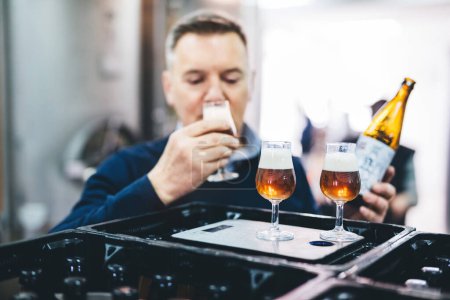 Man tasting craft beer from brewery. Middle-aged business owner, expert.