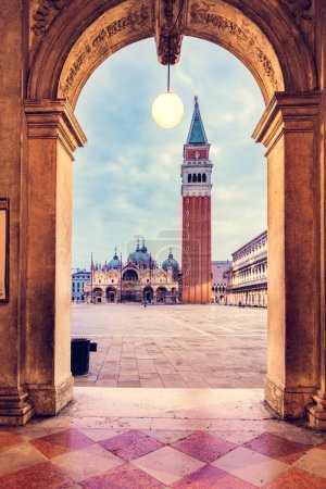 Arch columns on Piazza San Marco with basilica and Campanile tower in Venice, Italy at sunrise