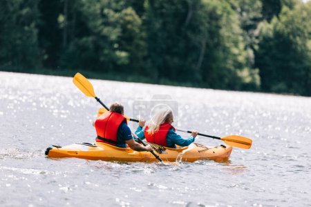 Happy senior active couple kayaking on lake enjoying time together