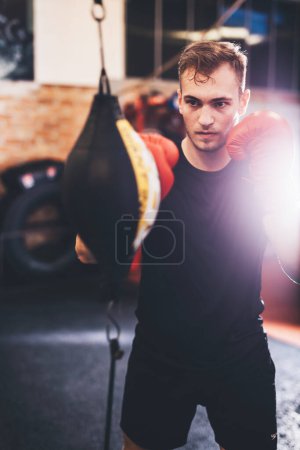 Boxer do boxing training with punchbag on a gym