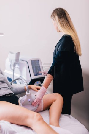Beauty salon client, a woman getting a cryolipolysis procedure on her thigh to reduce fat by a beautician.