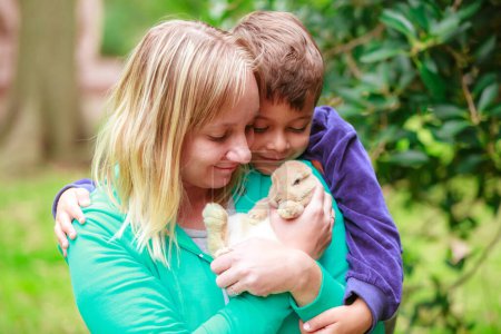 Téléchargez les photos : Happy family with a rabbit in their hands in the park - en image libre de droit