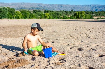 Téléchargez les photos : Little boy on the beach playing in the sand - en image libre de droit