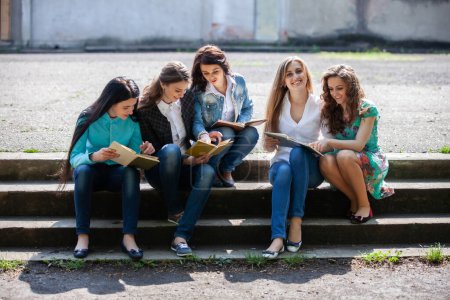Foto de Un grupo de alumnas sentadas con libros en el patio de la universidad - Imagen libre de derechos