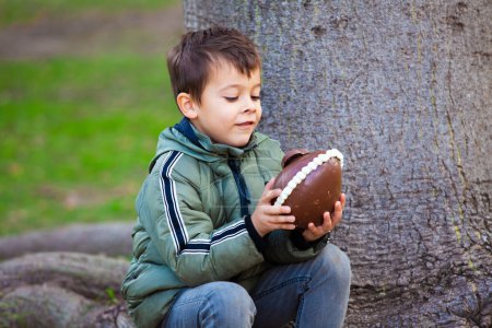 Photo for Happy little boy with easter chocolate egg in the park - Royalty Free Image