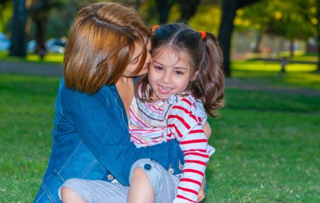 Téléchargez les photos : Mère heureuse avec sa fille sur la pelouse du parc - en image libre de droit