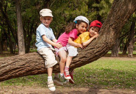 Téléchargez les photos : Les petits enfants s'assoient sur un arbre dans le parc - en image libre de droit