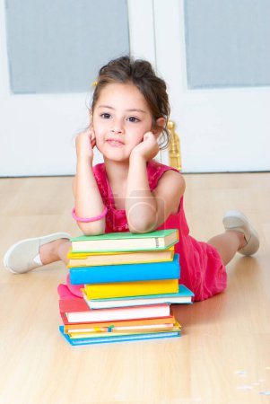 Photo for Girl with books sitting on the floor in kindergarten - Royalty Free Image