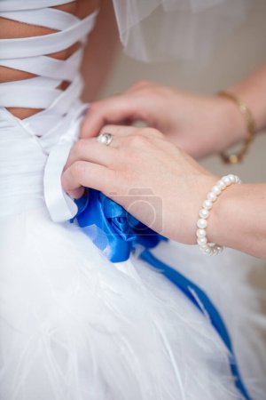 Téléchargez les photos : Mains féminines attachant un arc de mariage sur la robe de la mariée - en image libre de droit