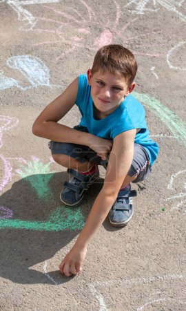 Téléchargez les photos : Dessin garçon à la craie sur asphalte - en image libre de droit