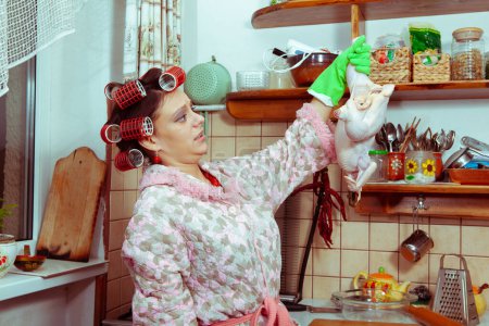 Téléchargez les photos : Femme au foyer avec un poulet dans la cuisine - en image libre de droit