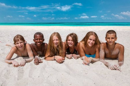 Téléchargez les photos : Groupe joyeux d'enfants sur la plage de sable fin - en image libre de droit